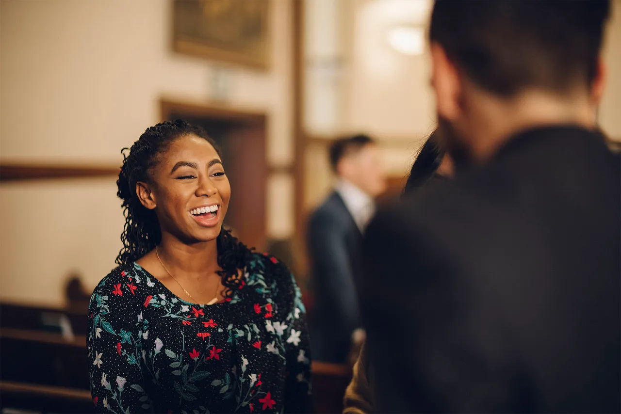 A woman smiling speaks with a man at church