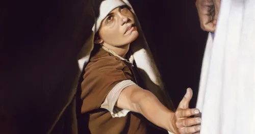 woman reaching to touch Jesus’s robe