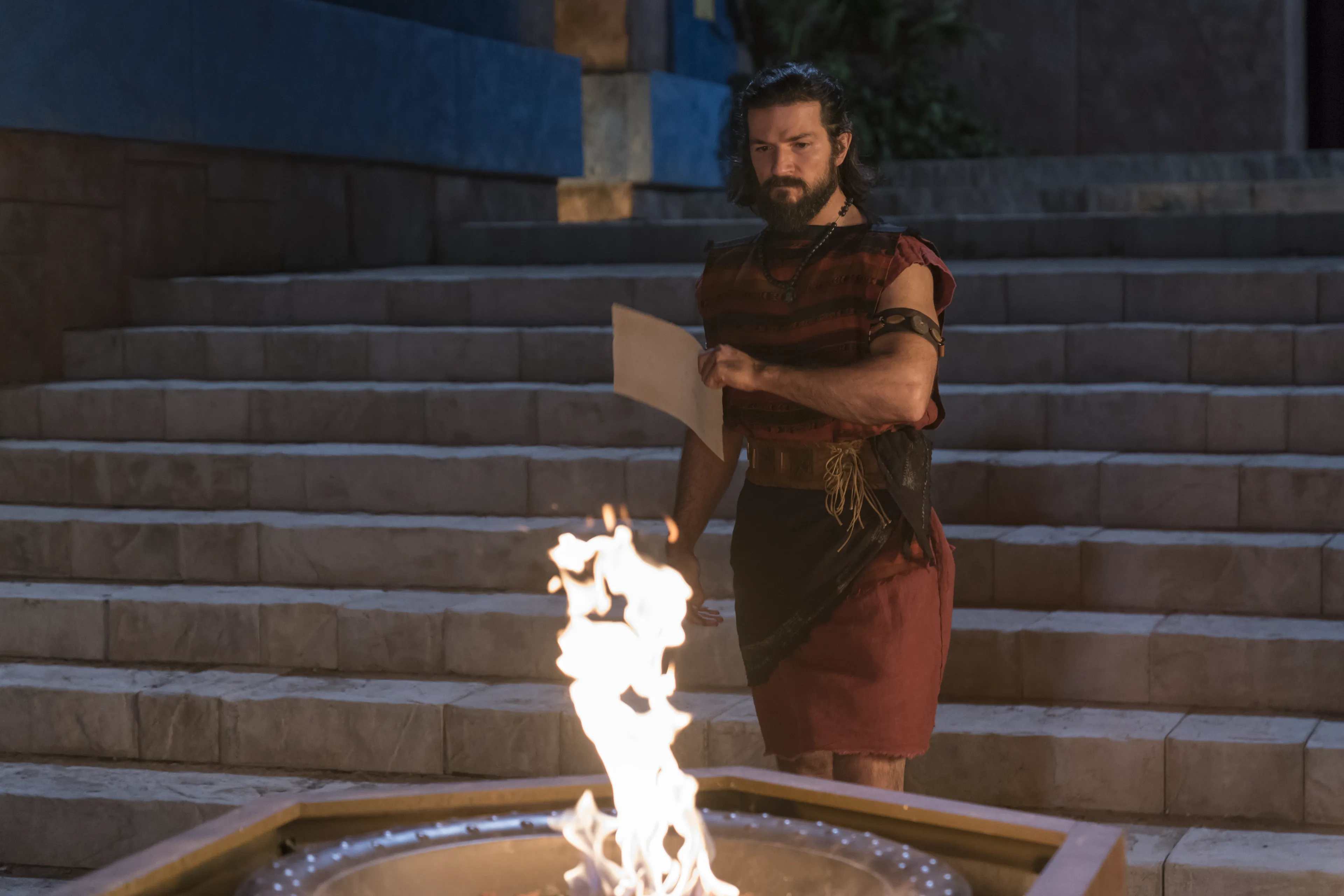 Alma the Younger approaches a fire while carrying a parchment.