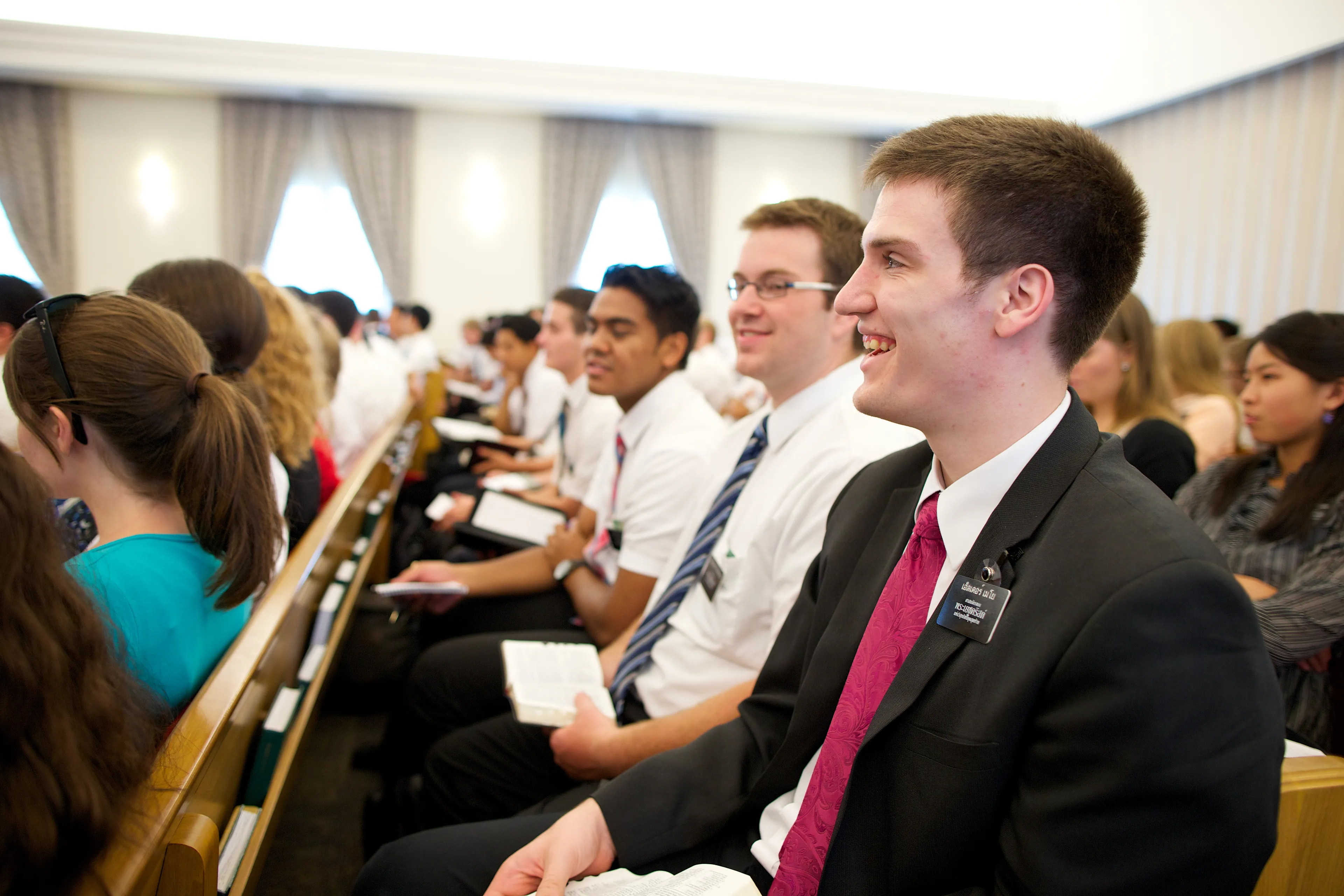 Elder and sister missionaries sitting in a chapel during zone conference.