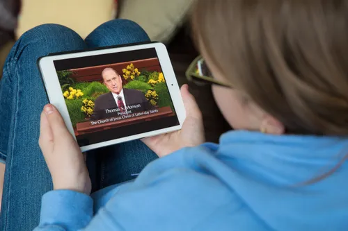 young woman looking at screen of President Monson