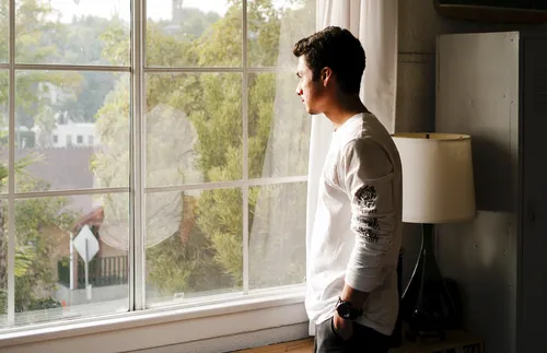 young man looking out window