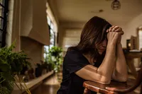 A young woman kneels in prayer