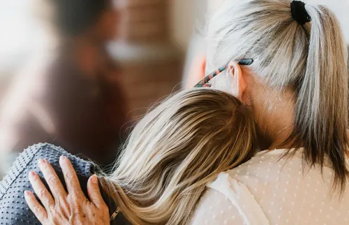a young woman resting her head on the shoulder of an older woman