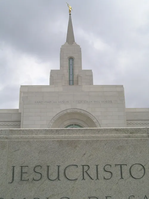 The spire of the San Salvador El Salvador Temple, with the angel Moroni on top and with a partial view of the temple name sign.