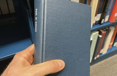 hand holding a copy of the Book of Mormon