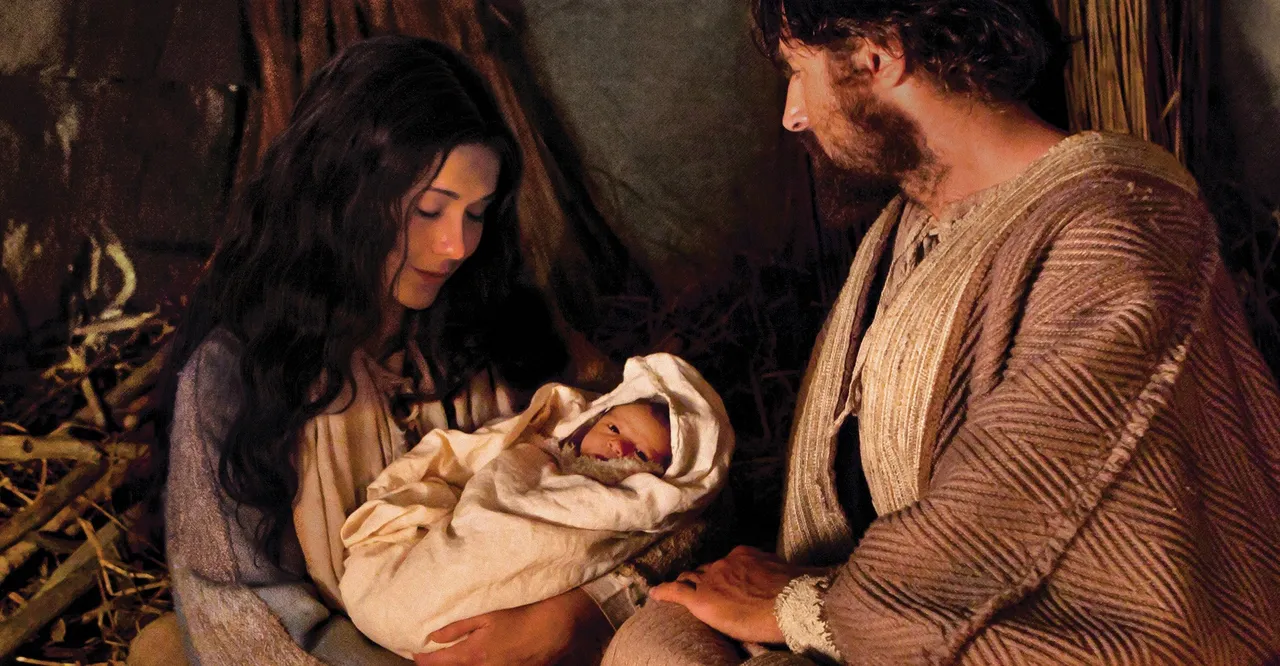 Mary holds the newborn Jesus Christ in the stable with Joseph