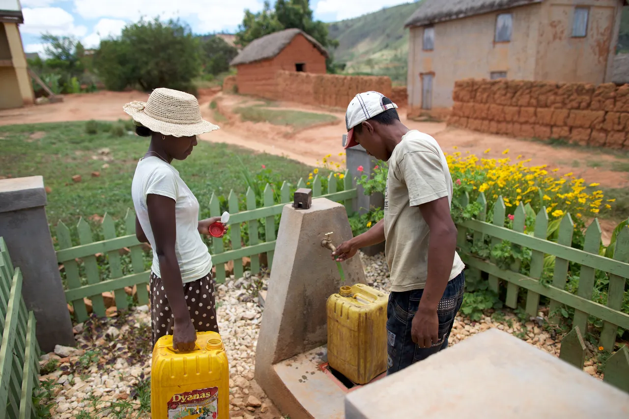 Two people retrieve clean drinking water from a well