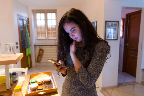 a young woman looking at her phone in the kitchen