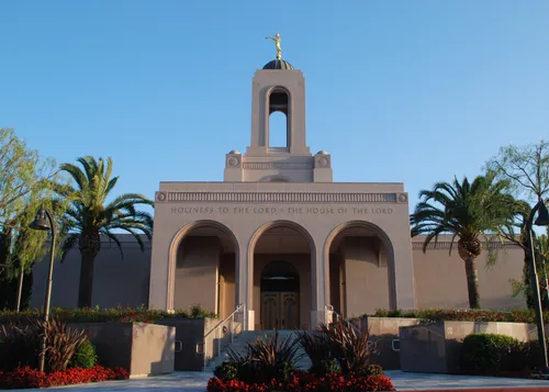 The front entrance of the Newport Beach California Temple in the late afternoon, with palm trees growing near the doors.