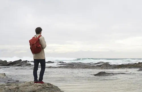man looking out to sea from coastal rocks