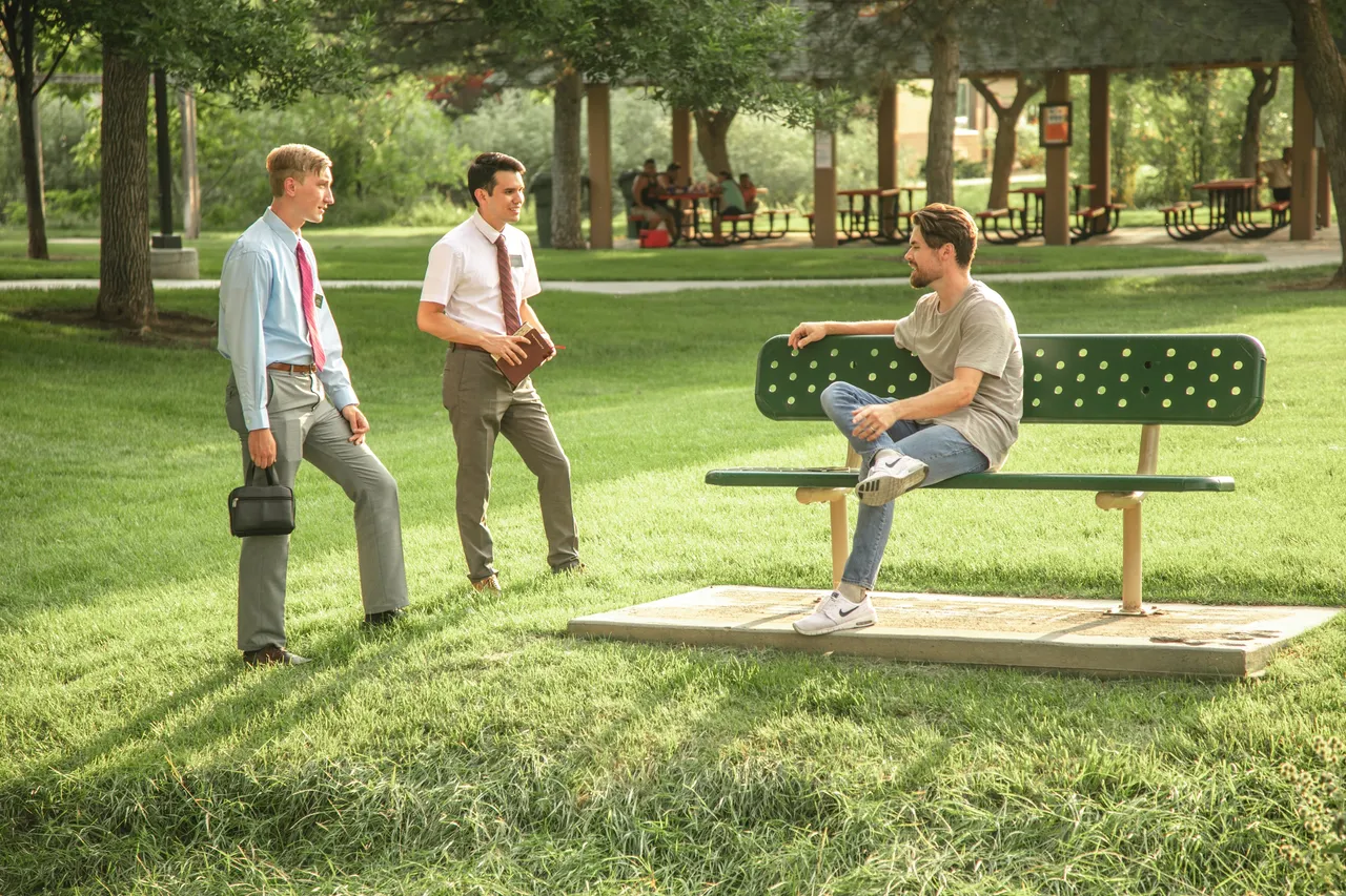Missionaries teaching a young man in the park about Jesus Christ