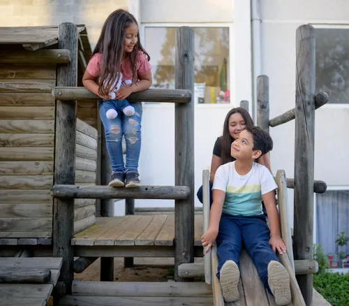 Santiago and his sisters playing on a wooden playscape