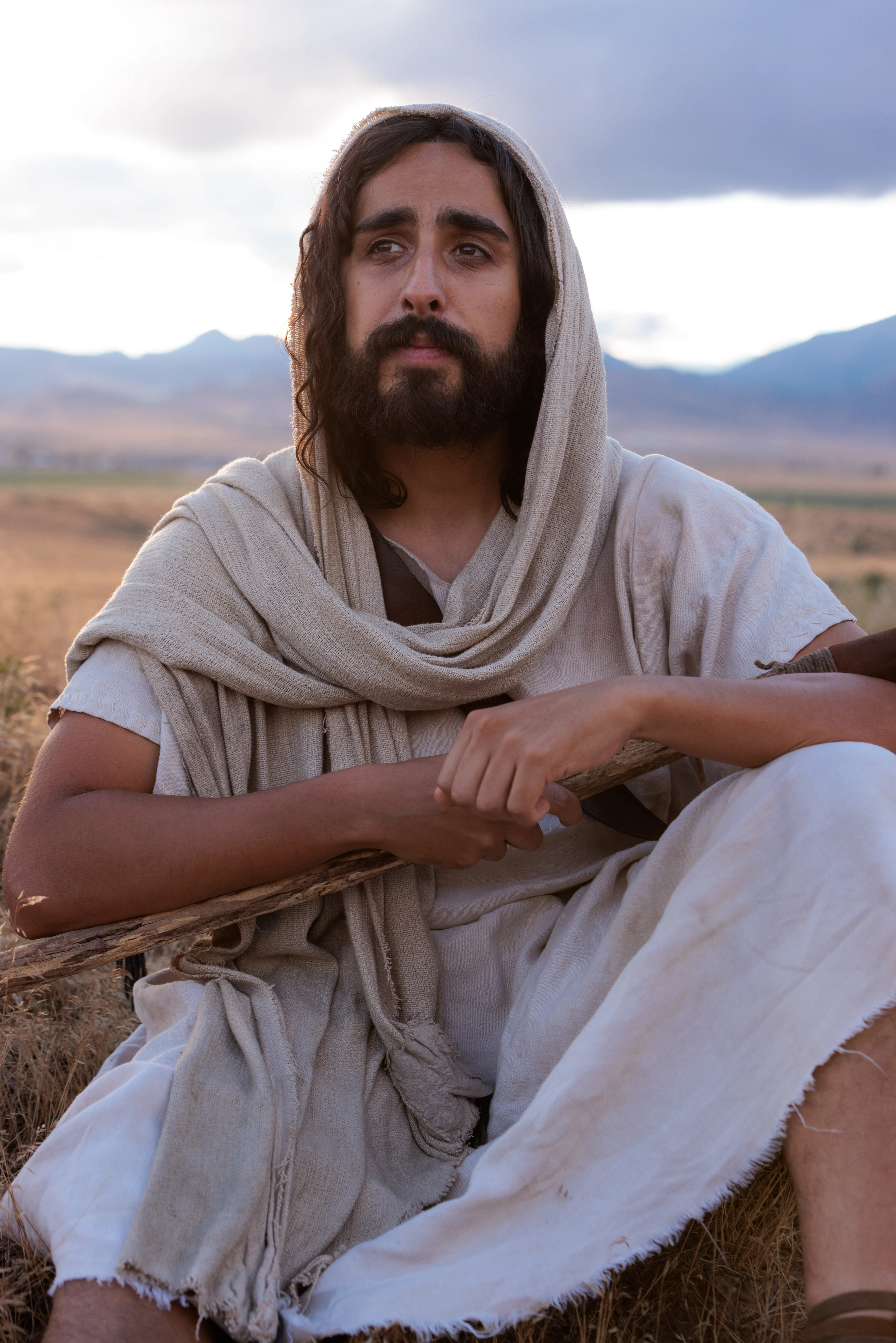 Depiction of Jesus Christ sitting in a field holding His shepherd staff. Detail from the Easter 2026 campaign. © undefined ipCode 1.