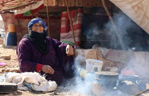 woman cooking a meal outside a temporary shelter