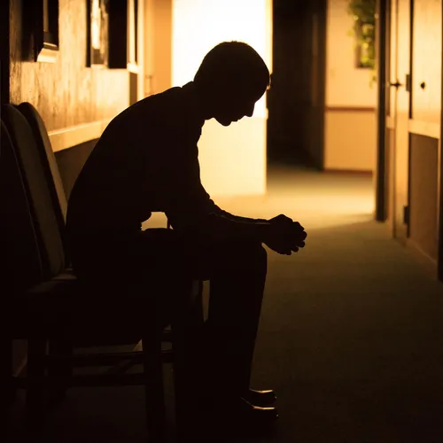 young man sitting with head bowed