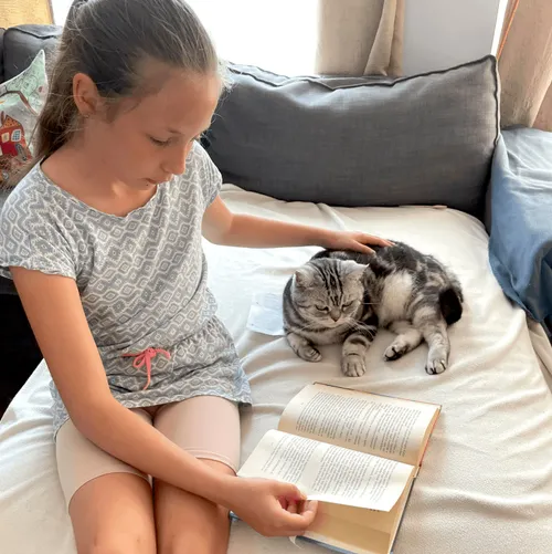 Girl petting cat and reading the scriptures