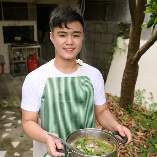 young man with pot full of soup