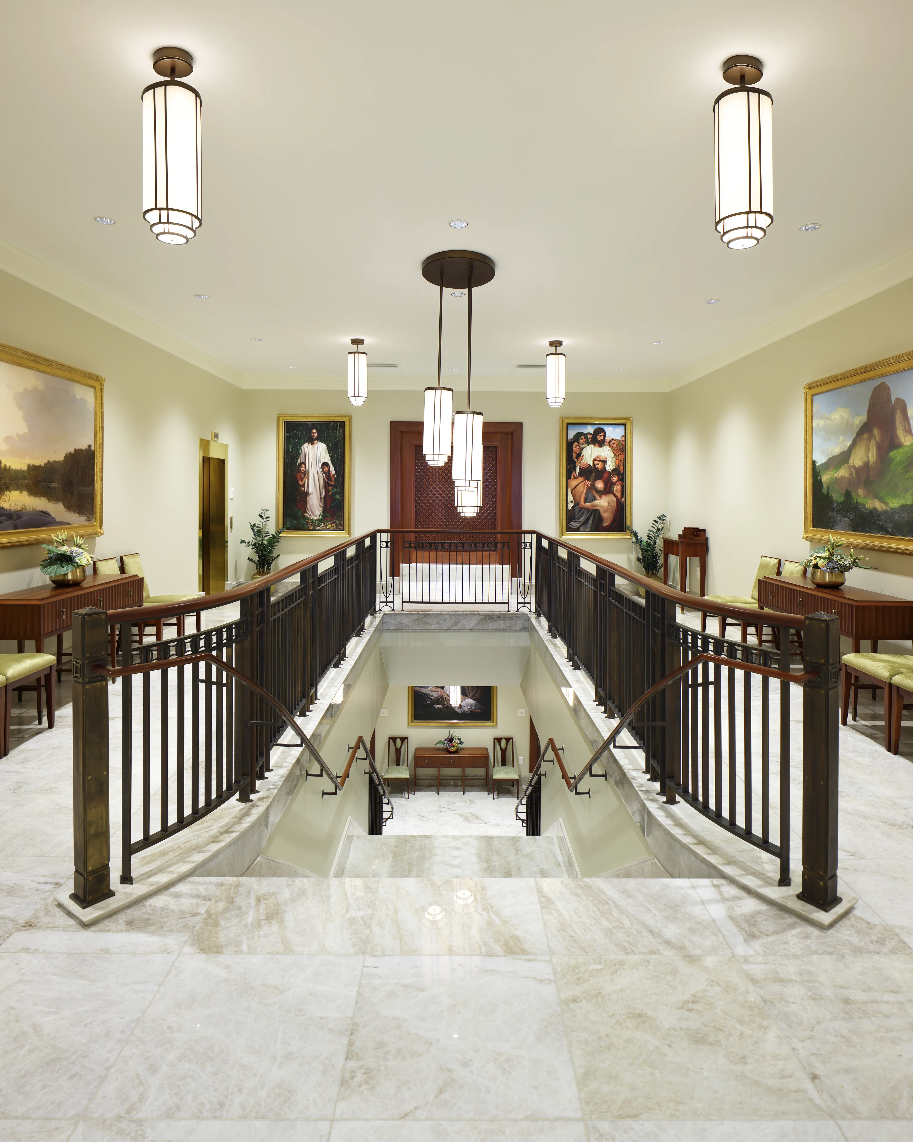 Interior image of the Abidjan Ivory Coast Temple featuring the Grand Staircase. The image is from the stop of the staircase looking out. You see temple art on the walls and the stairs going downstairs. © undefined ipCode 1.