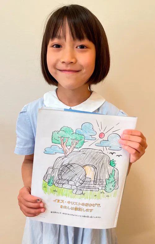 Photo of smiling girl holding up a finished coloring page