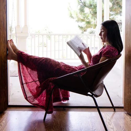 a woman sitting in a chair and reading her scriptures
