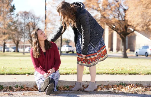 a young adult coming to sit next to another young adult