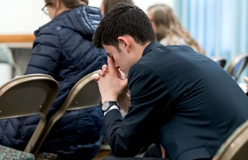 a young missionary praying alone at church
