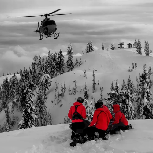 first responders waiting for a helicopter to land on a snowy mountain