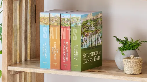 Picture of the book series, 'Saints' volume 1-4 (English edition). Four volumes are arranged on the middle shelf of a wooden bookshelf along with plants.