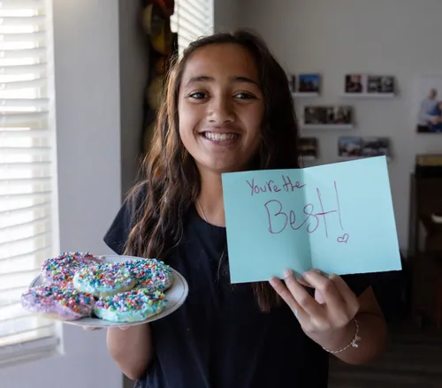 Girl holding a plate of cookies and a handwritten card