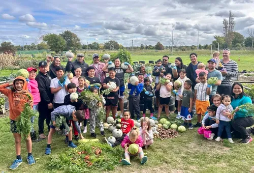 Photo of a group of Primary children outdoors with various vegetables