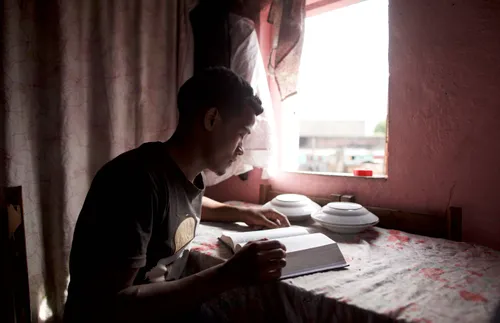 a young man sitting at a table and reading the scriptures