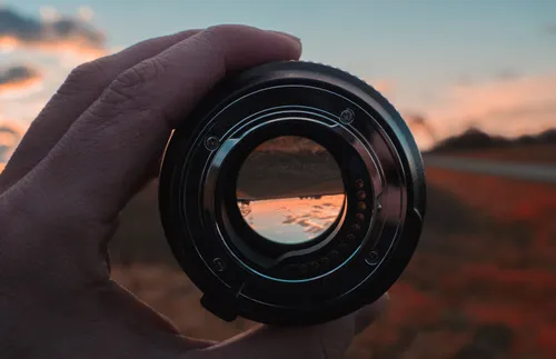 a hand holding a camera lens