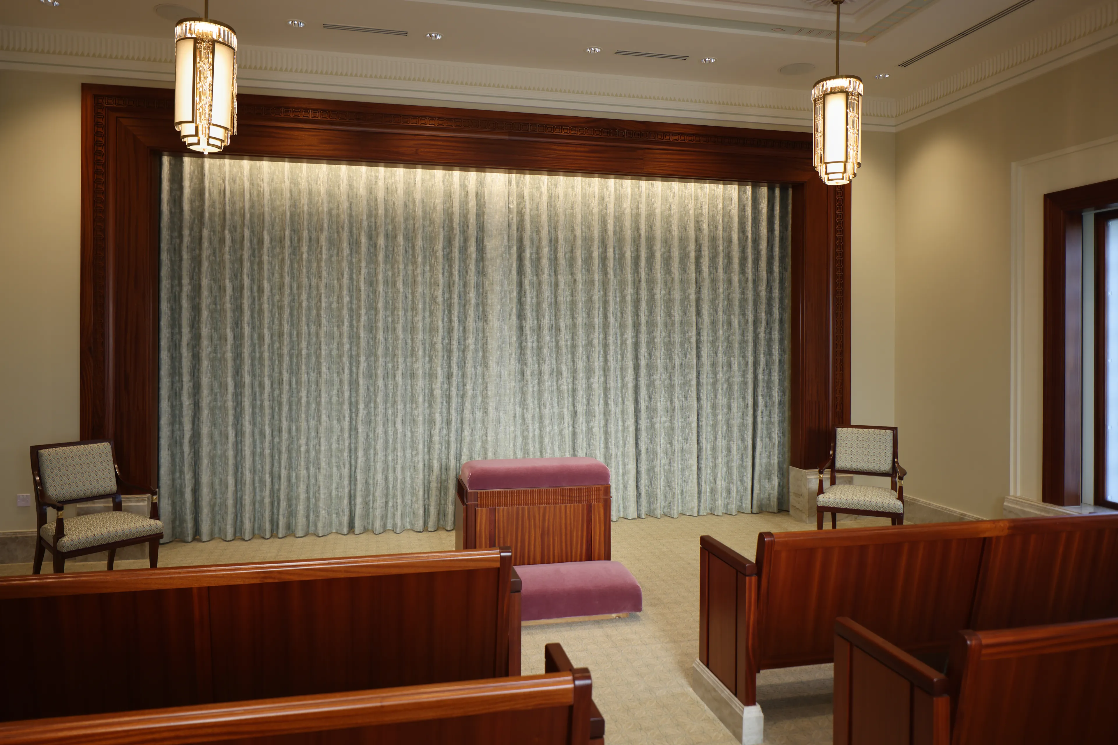 Interior image of the Abidjan Ivory Coast Temple featuring an Ordinance Room/Instruction Room. There are pews to two sides, an altar in the front, and a veil behind the altar. © undefined ipCode 1.