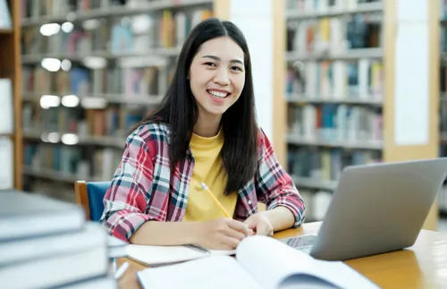 a student sitting at a table with a computer and a notebook