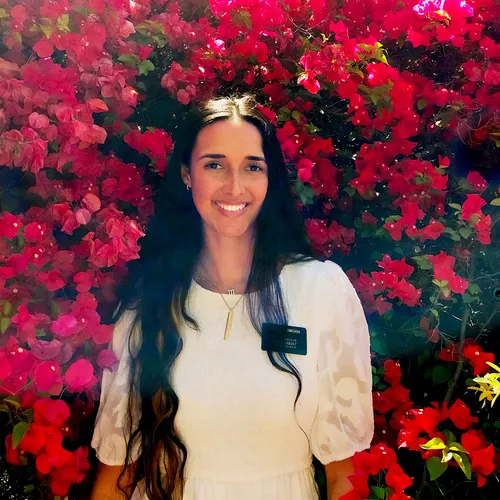 a young female missionary standing in front of pink flowers