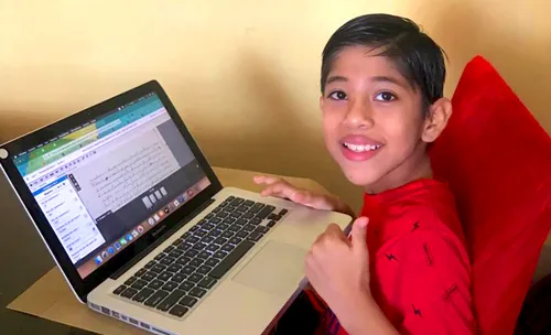 Josué E. with a computer and giving a thumbs-up sign