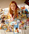 Smiling girl surrounded by copies of the Friend magazine