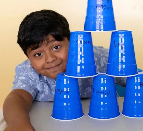 boy with a pyramid made out of stacked plastic cups