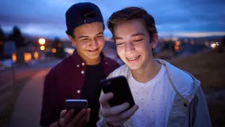 Two young men share experiences on a smartphone.