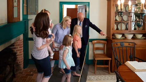 Various people visit the Kirtland Visitors Center. They look at art and artifacts that are up on the walls and around the homes and rooms. Various families look around at rooms full of artifacts.
Historic Kirtland Visitors' Center, families, children, interiors, Artifacts/Replicas