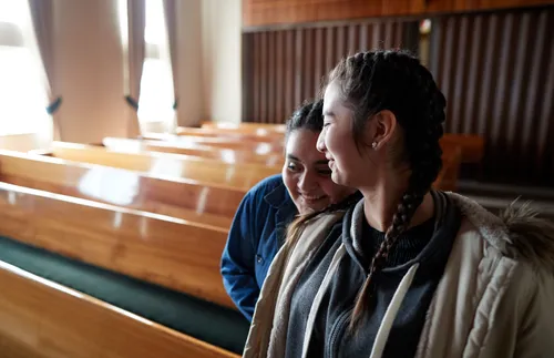 two women sitting and smiling together in a church building
