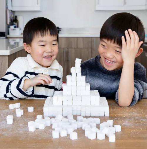 Two children building a temple craft out of sugar cubes