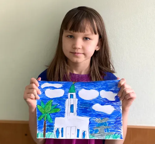 Girl holding a picture she drew of a temple