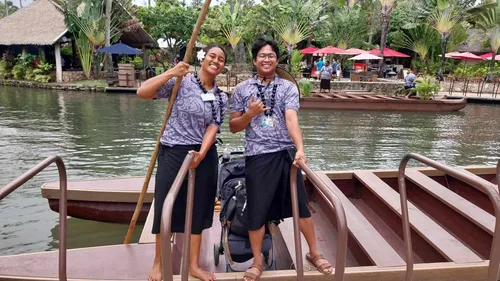 two young adults smiling and standing in front of a canoe