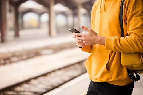 person using phone near train tracks