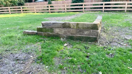 Stones stack atop one another sitting in a sparse grass field.