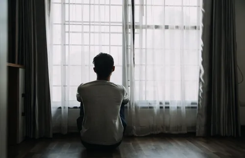 a young man sitting and looking out a window