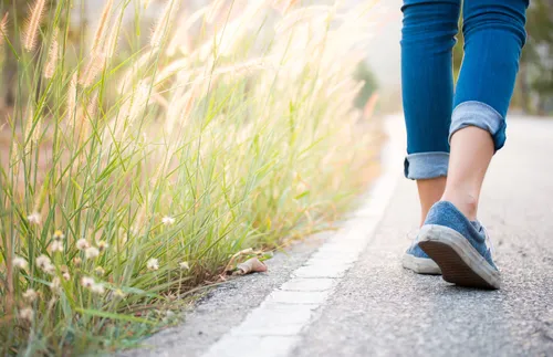 view of a person’s feet walking down a road
