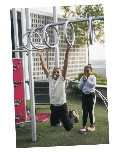 Billede af en bror og søster, der leger på en legeplads